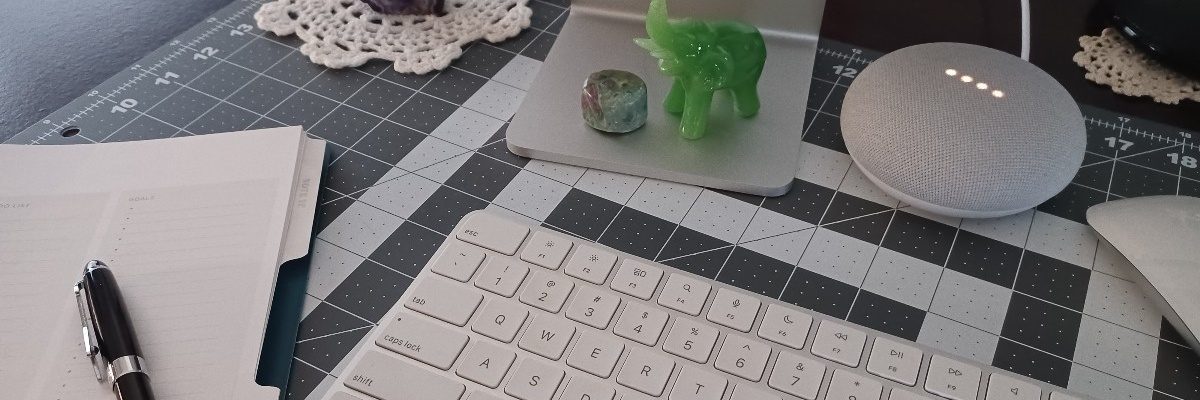 A writer's desk with pen, planner, keyboard, and decorations.